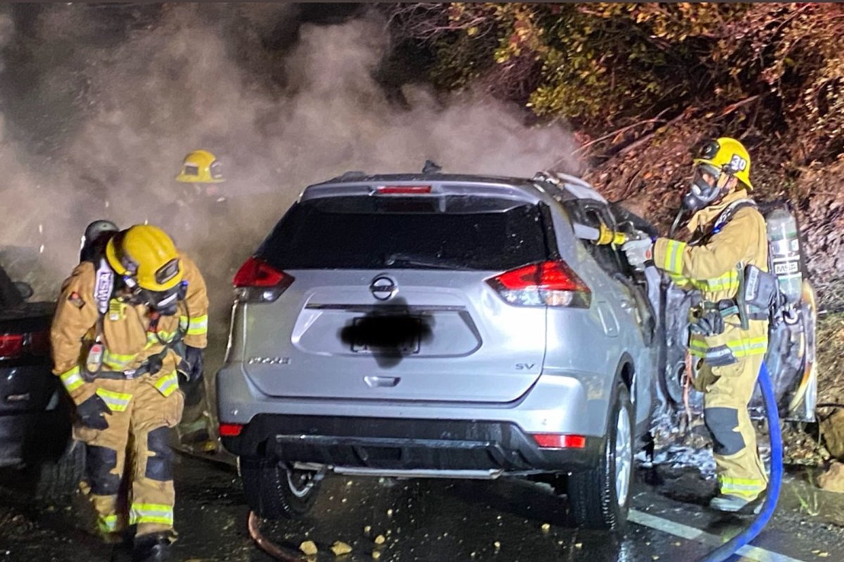 Firefighters douse flames in a vehicle that caught fire following a collision early Sunday on Highway 154 near Lake Cachuma.